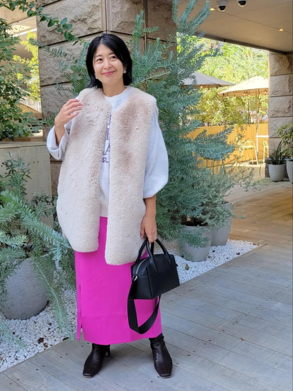 ベージュ系のベスト、ピンク系のスカートを着用したレディースの秋コーディネートの2枚目の写真