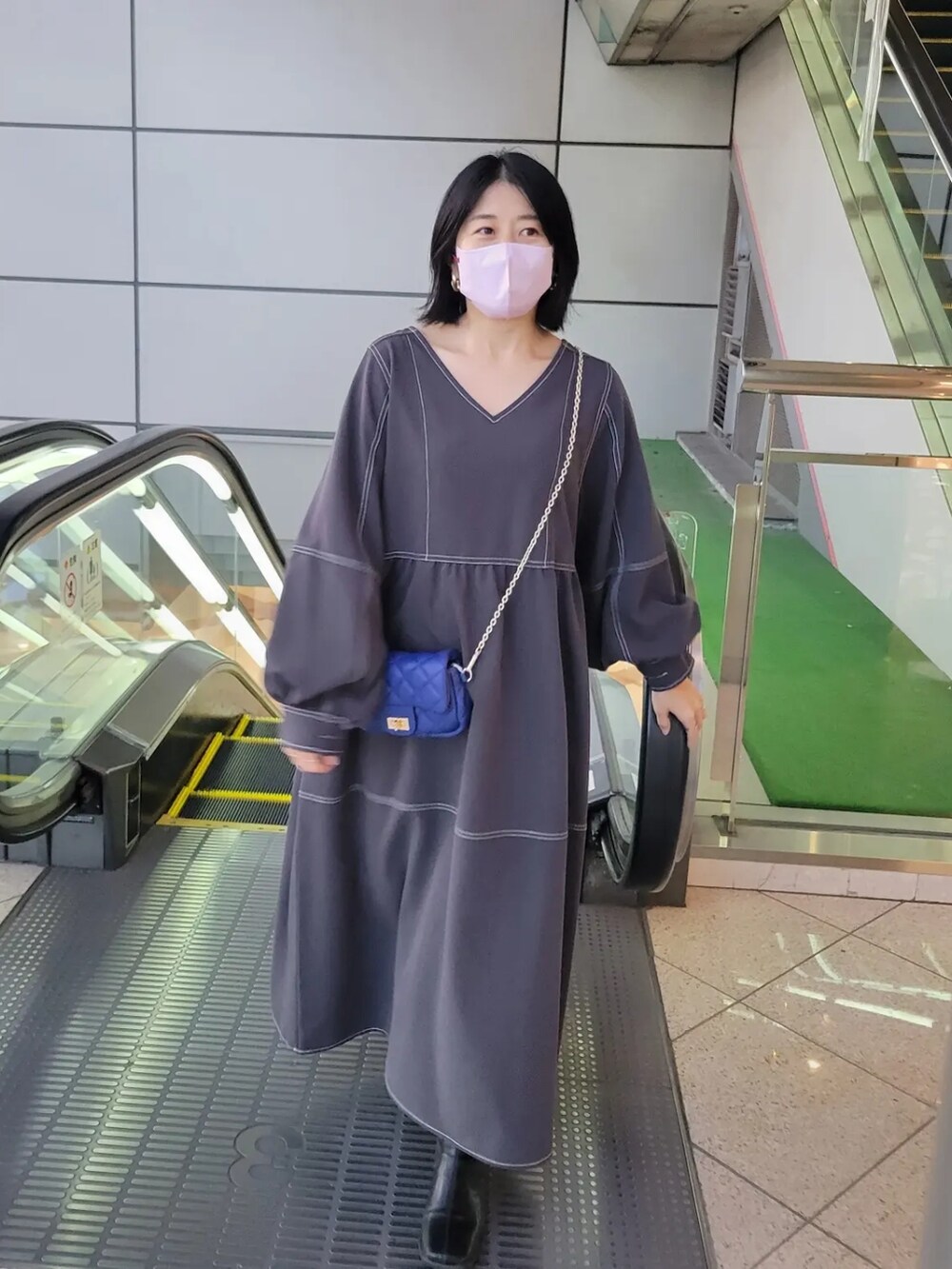 グレー系のワンピース、ブルー系のショルダーバッグを着用したレディースの秋コーディネートの2枚目の写真