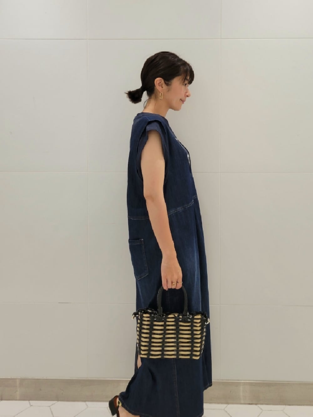 ブラック系のショルダーバッグ、ブルー系のジャンパースカート、ブルー系のTシャツ/カットソーを着用したレディースの夏コーディネートの2枚目の写真