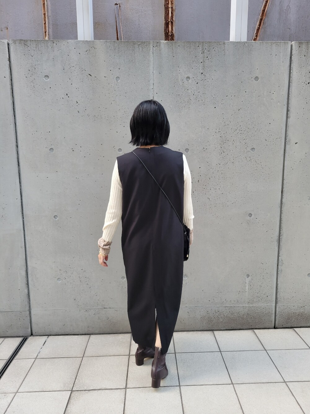 ブラック系のジャンパースカート、ホワイト系のニット/セーターを着用したレディースの秋コーディネートの3枚目の写真