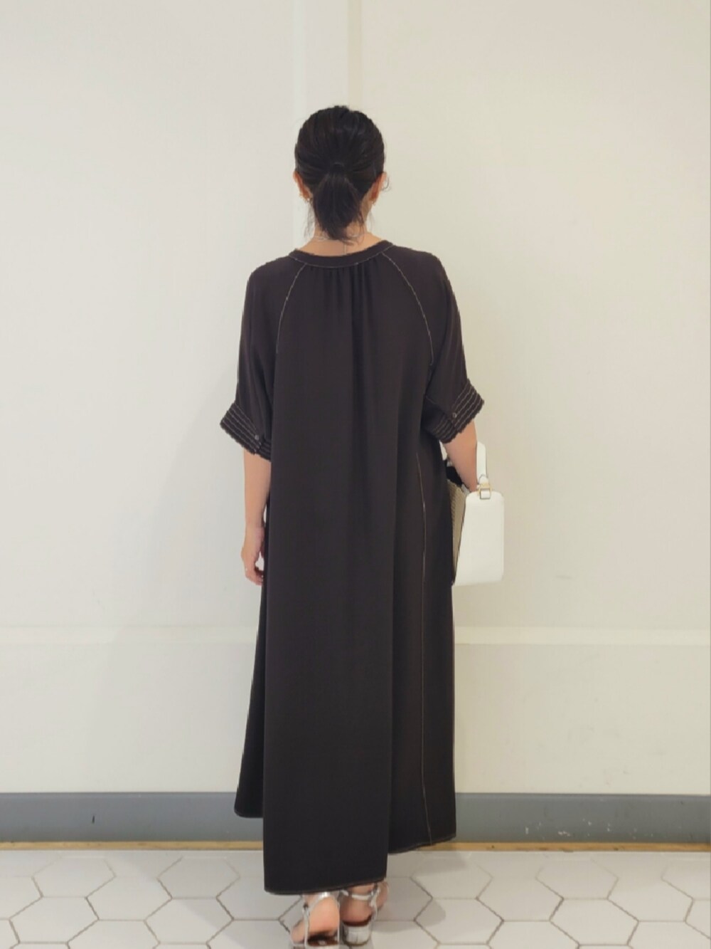 シルバー系のシューズ、ブラウン系のワンピース、ホワイト系のショルダーバッグを着用したレディースの春コーディネートの3枚目の写真