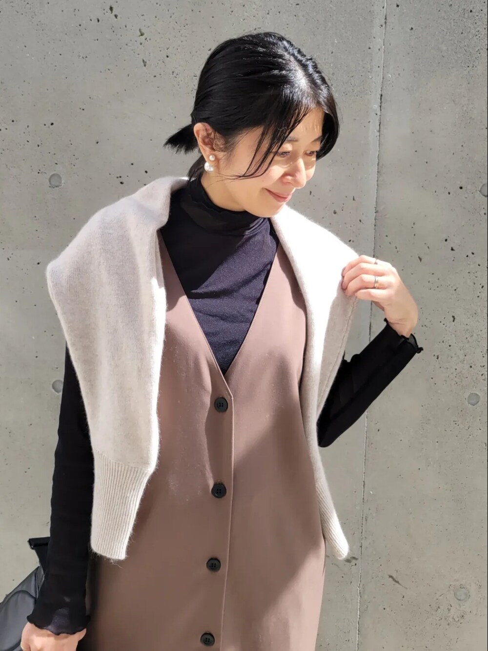 ブラック系のショルダーバッグ、ブラウン系のジャンパースカート、ブラック系のTシャツ/カットソーを着用したレディースの秋コーディネートの3枚目の写真