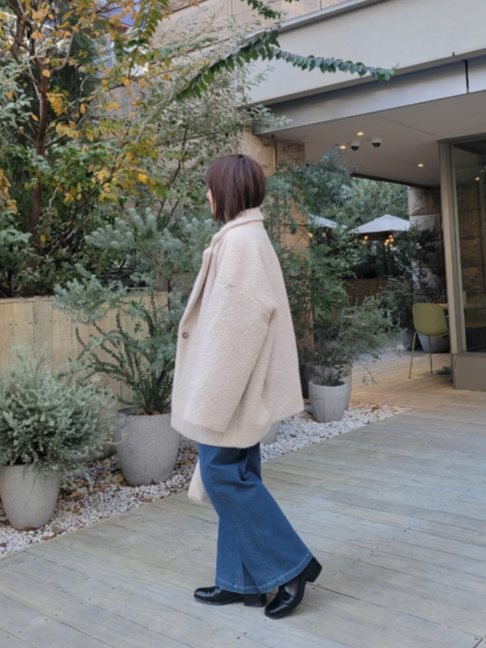 ブルー系のデニムパンツ、ブルー系のニット/セーター、ベージュ系のその他アウターを着用したレディースの冬コーディネートの2枚目の写真