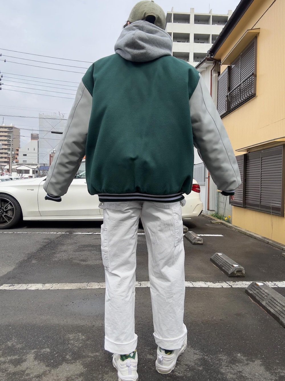 グリーン系のスタジャン、グレー系のパーカー、ホワイト系のカーゴパンツを着用したメンズの春コーディネートの3枚目の写真