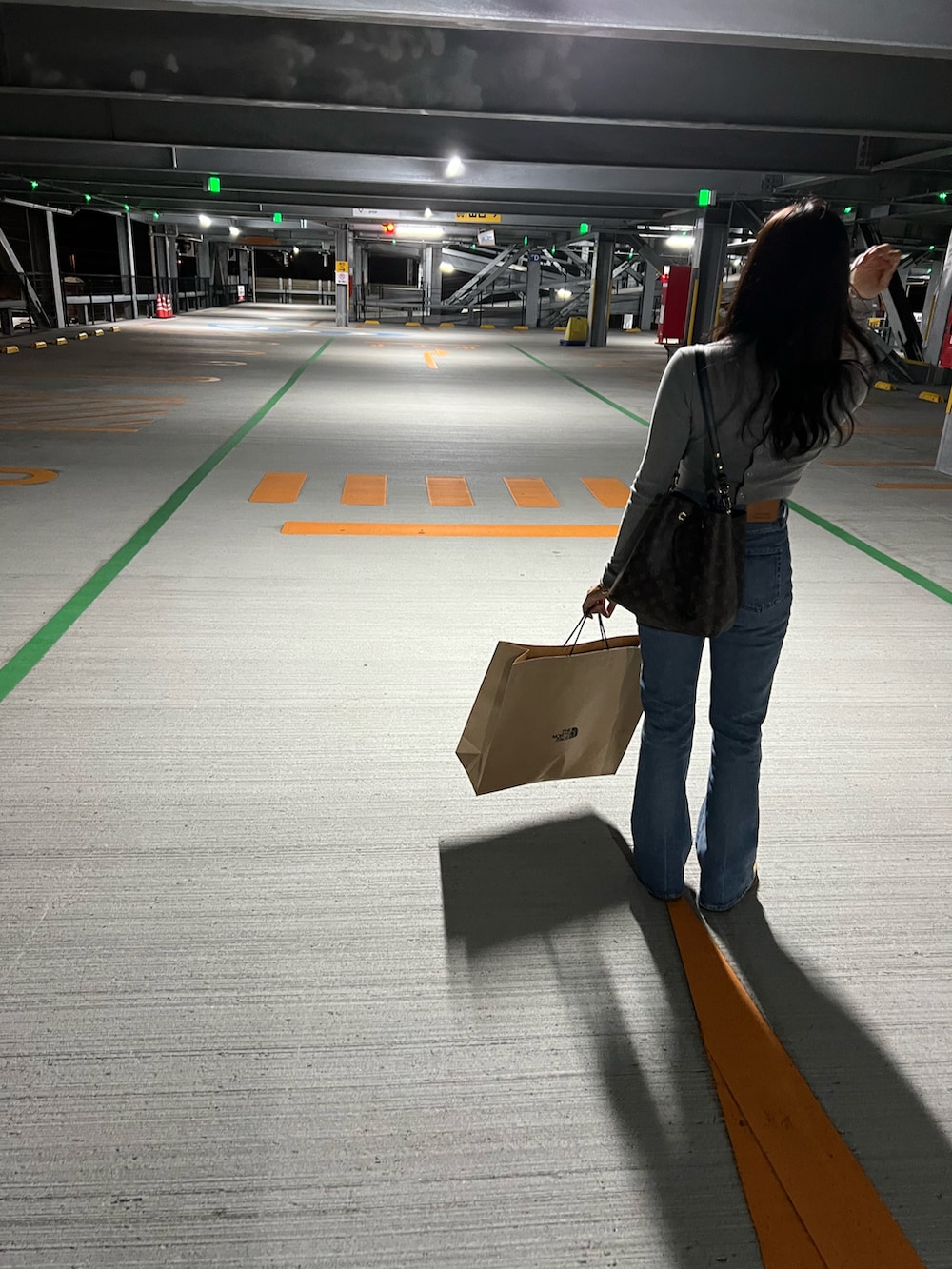 ブルー系のデニムパンツ、ベージュ系のブーツ、ブラック系のバッグを着用したレディースの秋コーディネートの2枚目の写真