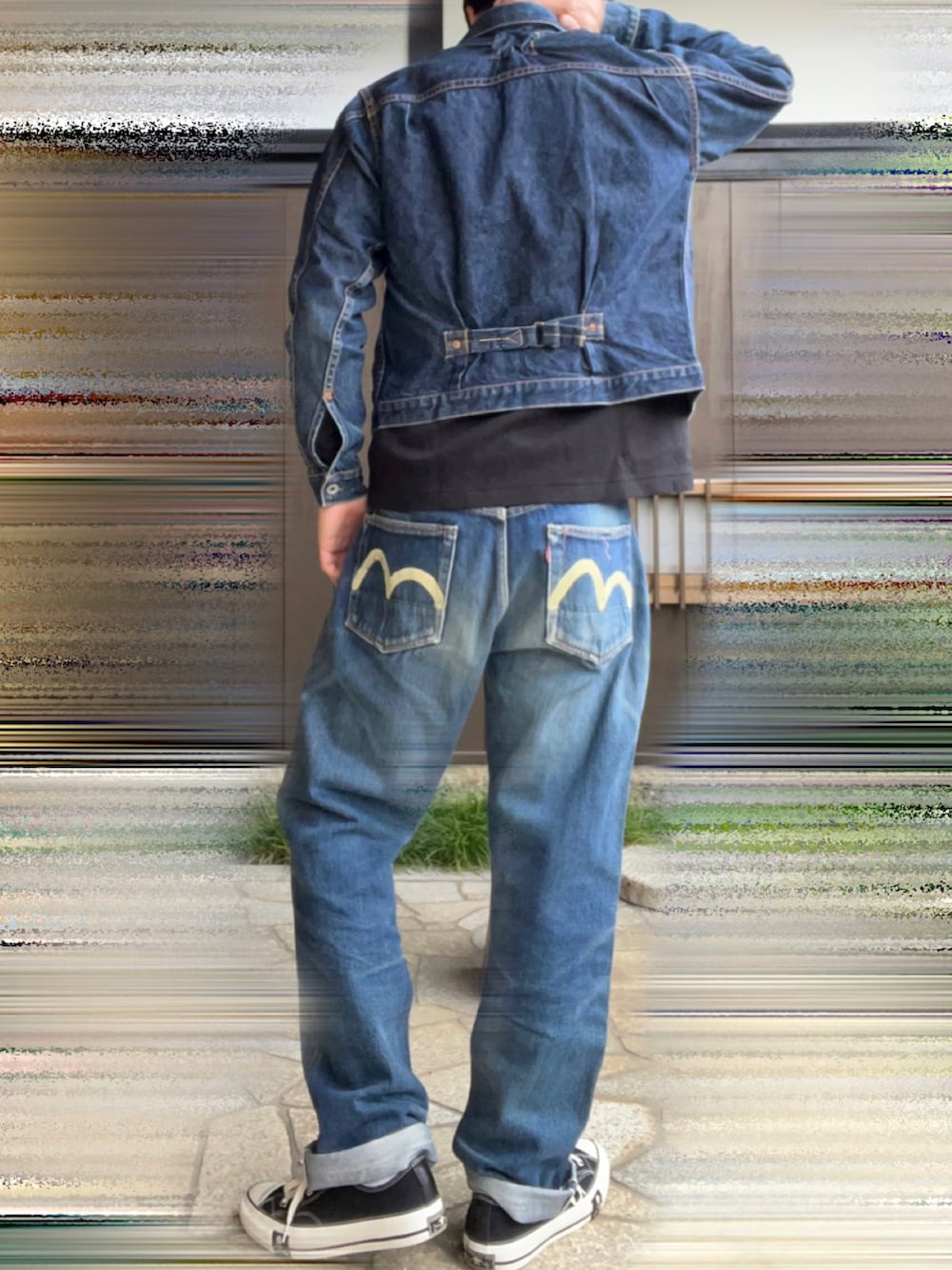 ブルー系のデニムパンツ、ブラック系のスニーカー、ブラック系のトップスを着用したメンズの秋コーディネートの2枚目の写真