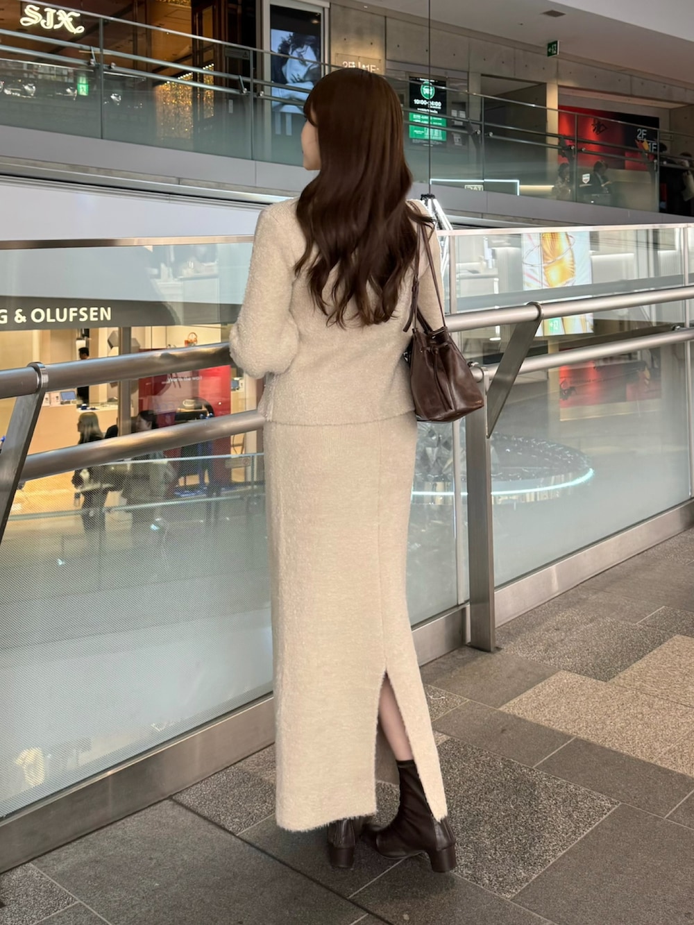 ベージュ系のカーディガン/ボレロ、ベージュ系のスカート、ブラウン系のショルダーバッグを着用したレディースの冬コーディネートの2枚目の写真