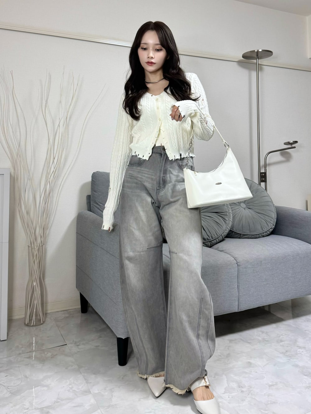 グレー系のデニムパンツ、ホワイト系のニット/セーター、ホワイト系のハンドバッグを着用したレディースの冬コーディネートの2枚目の写真