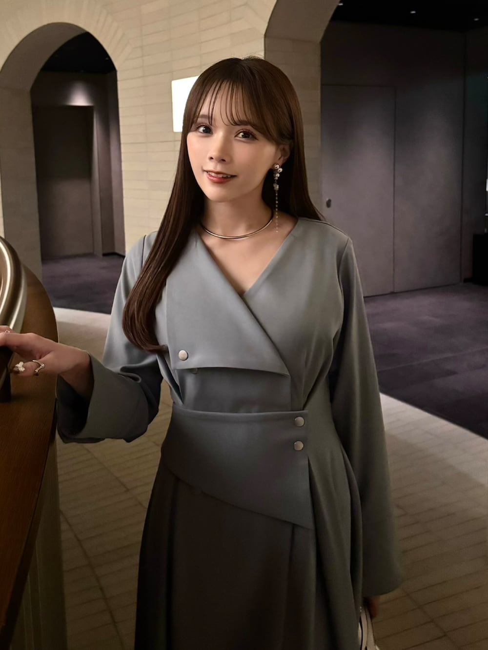 グレー系のワンピース、ホワイト系のステンカラーコート、ホワイト系のブーツを着用したレディースの冬コーディネートの4枚目の写真