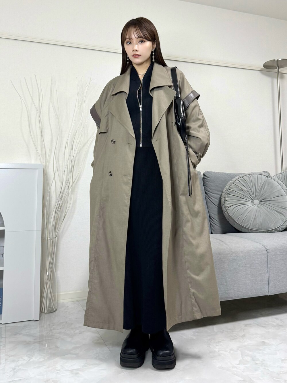 ブラック系のブルゾン、ブラック系のスカート、グレー系のトレンチコートを着用したレディースの秋コーディネートの2枚目の写真