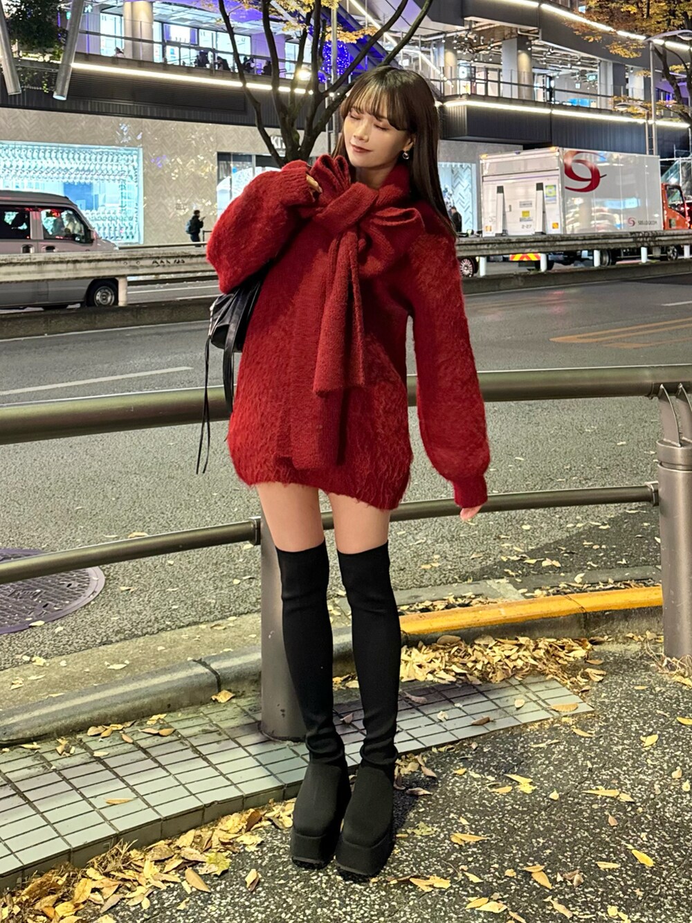 レッド系のワンピース、ブラック系のブーツ、ブラック系のバッグを着用したレディースの冬コーディネートの5枚目の写真