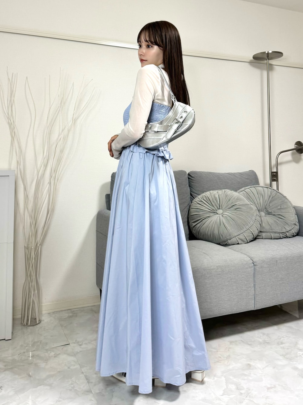 ブルー系のスカート、シルバー系のショルダーバッグ、ホワイト系のトップスを着用したレディースの春コーディネートの2枚目の写真