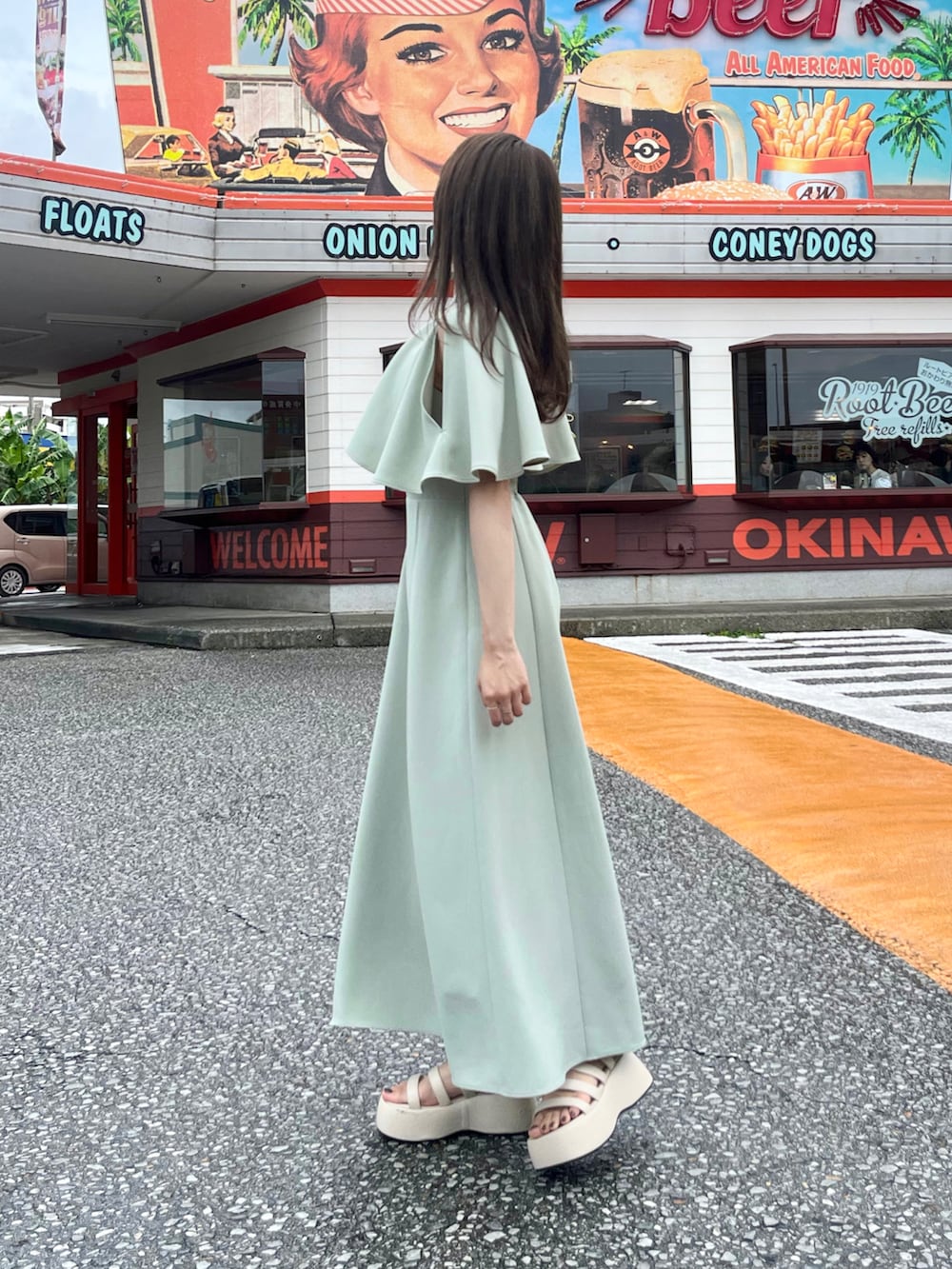 グリーン系のワンピース、ベージュ系のトートバッグ、ベージュ系のサンダルを着用したレディースの夏コーディネートの2枚目の写真