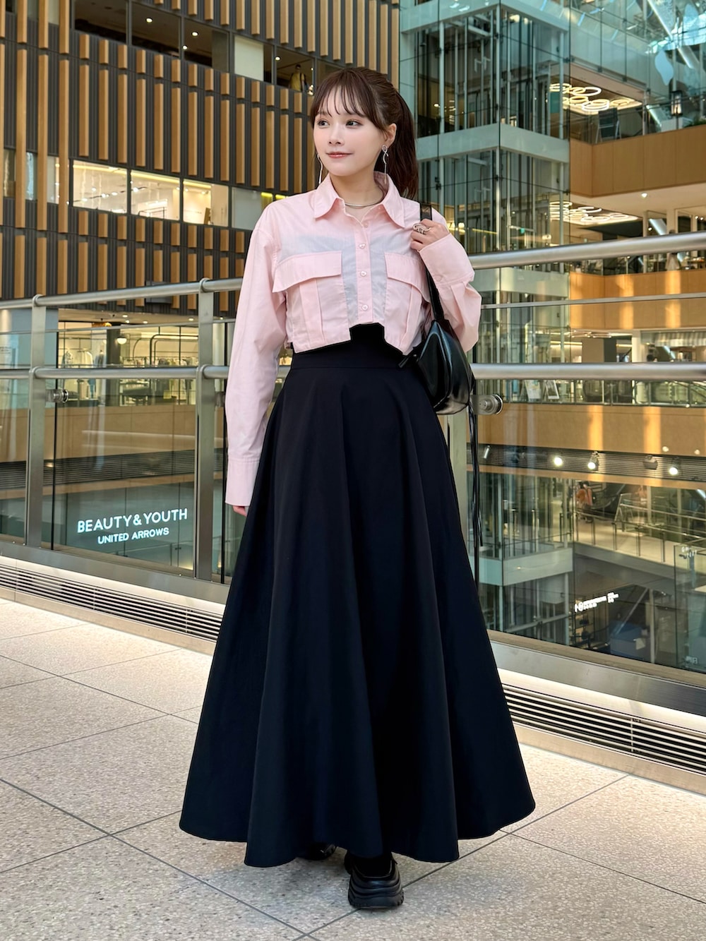 ブラック系のスカート、ピンク系のトップス、ブラック系のローファーを着用したレディースの春コーディネートの2枚目の写真