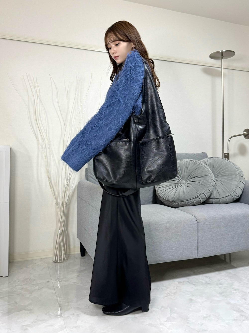 ブルー系のニット/セーター、ブラック系のトートバッグ、ブラック系のスカートを着用したレディースの秋コーディネートの3枚目の写真