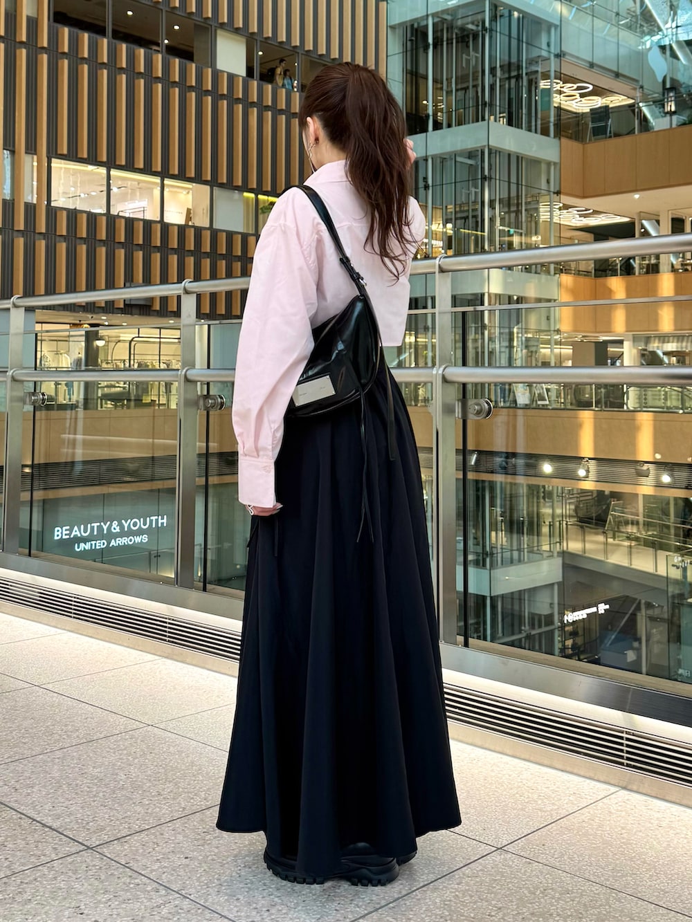 ブラック系のスカート、ピンク系のトップス、ブラック系のローファーを着用したレディースの春コーディネートの3枚目の写真