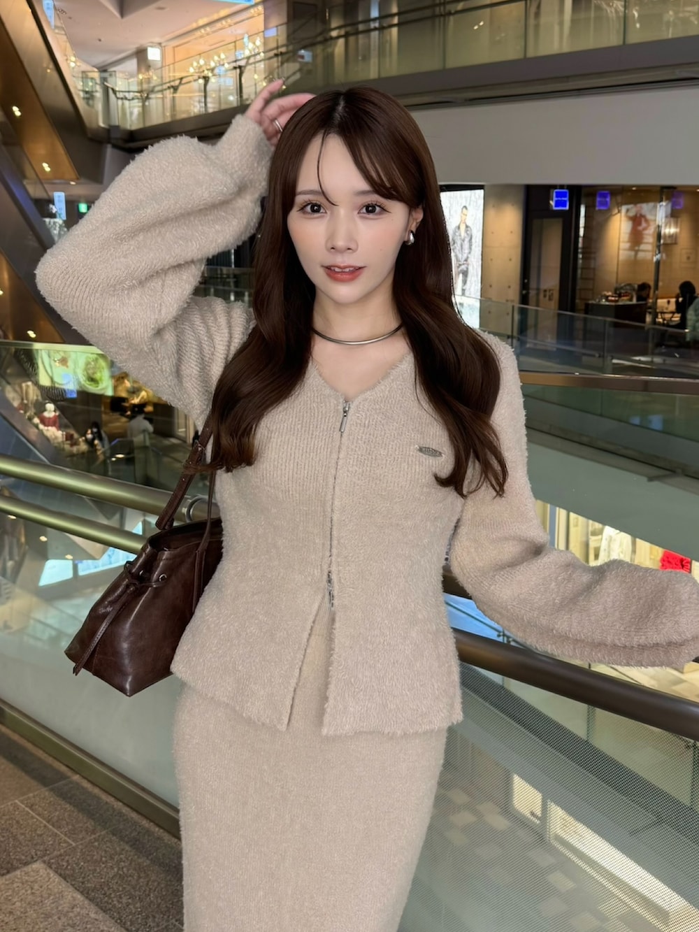 ベージュ系のカーディガン/ボレロ、ベージュ系のスカート、ブラウン系のショルダーバッグを着用したレディースの冬コーディネートの3枚目の写真