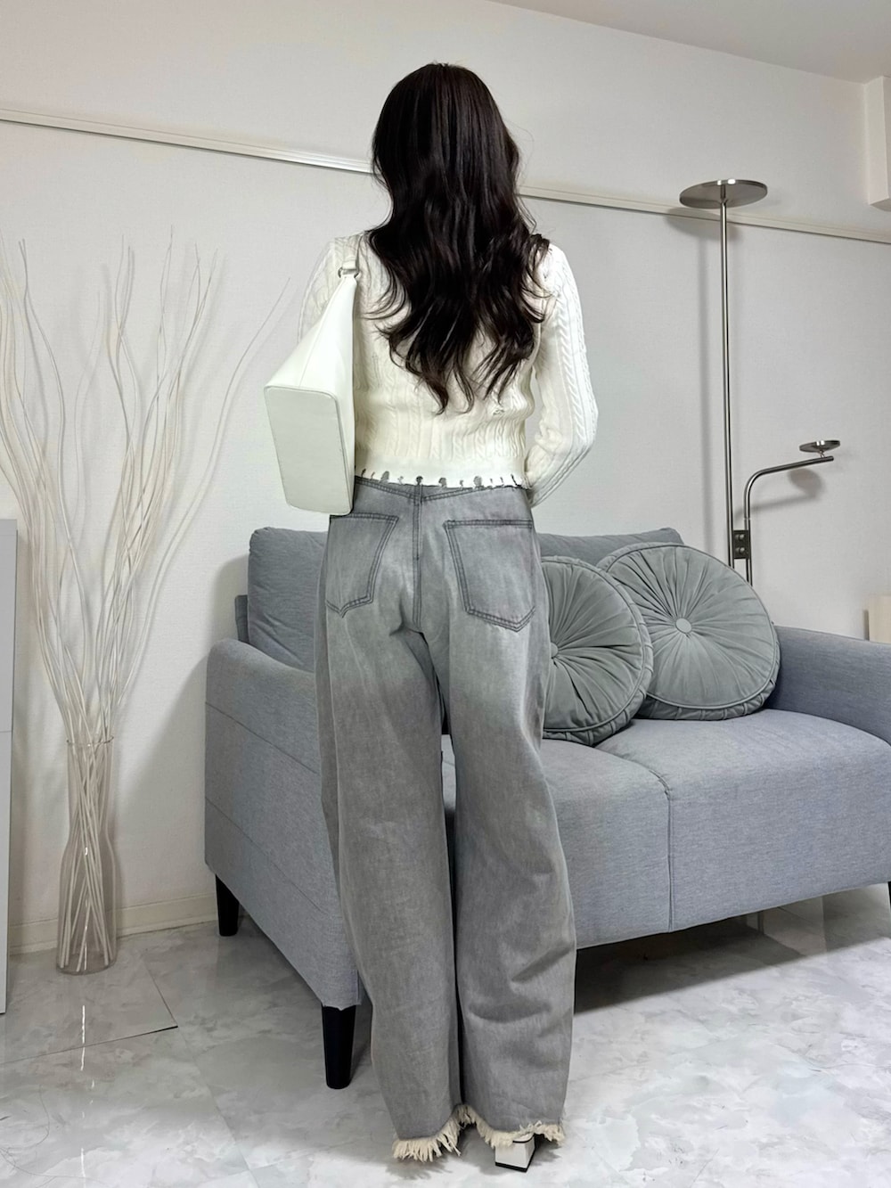 グレー系のデニムパンツ、ホワイト系のニット/セーター、ホワイト系のハンドバッグを着用したレディースの冬コーディネートの3枚目の写真