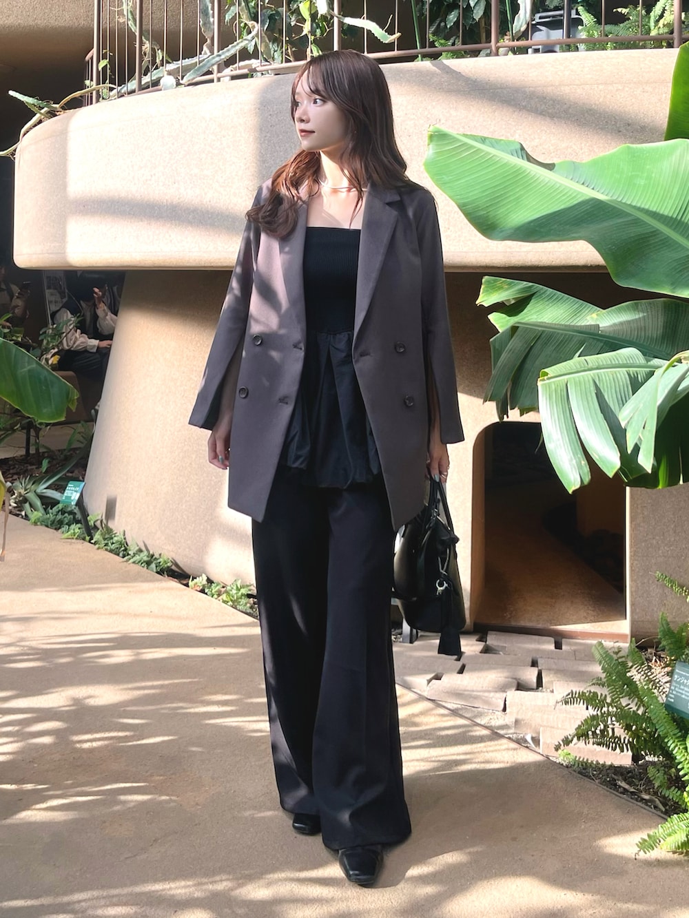 グレー系のテーラードジャケット、ブラック系のキャミソール、ブラック系のショルダーバッグを着用したレディースの春コーディネートの2枚目の写真