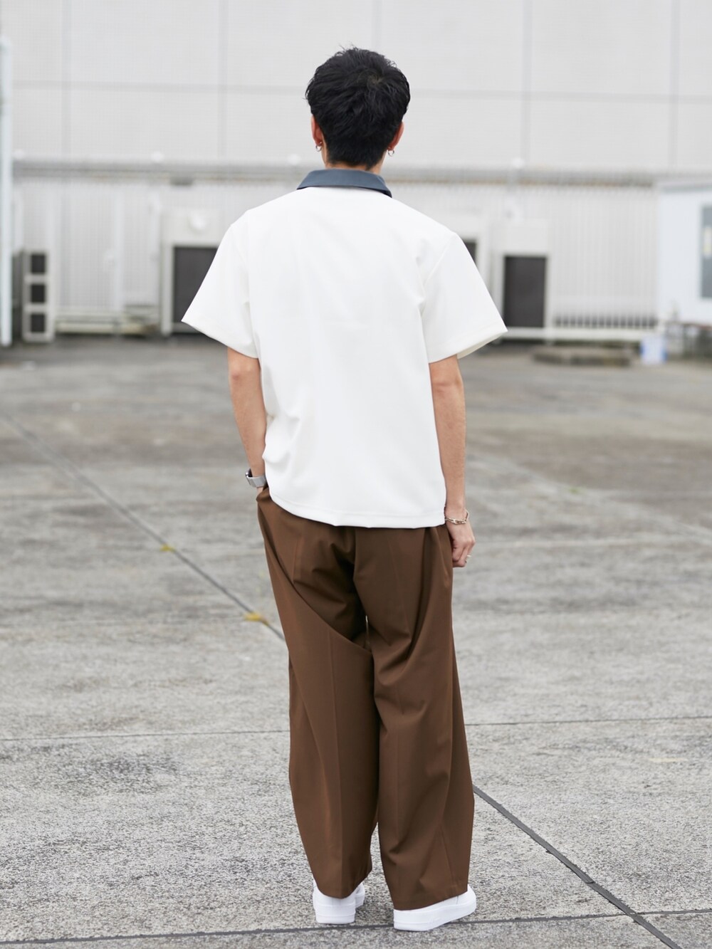 ホワイト系のポロシャツ、ブラウン系のスラックスを着用したメンズの春コーディネートの3枚目の写真