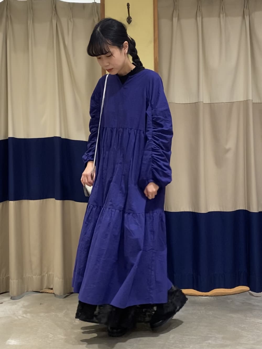 ブルー系のワンピース、ブラック系のスカート、シルバー系のハンドバッグを着用したレディースの冬コーディネートの2枚目の写真