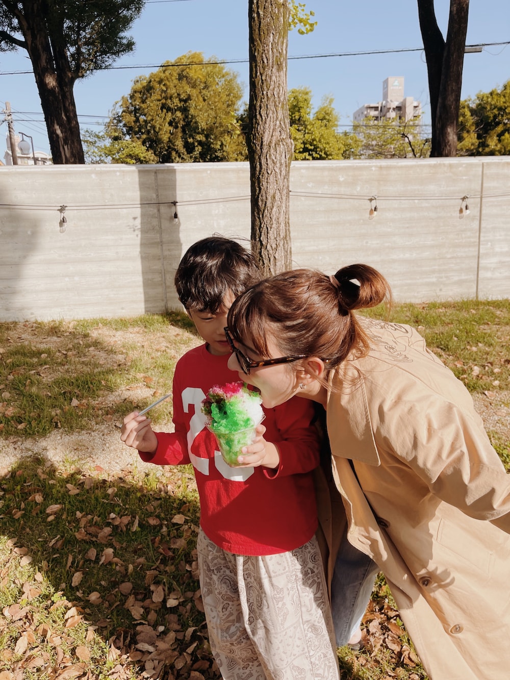 ブラック系のサンダル、ブルー系のデニムパンツ、レッド系のトートバッグを着用したレディースの春コーディネートの3枚目の写真