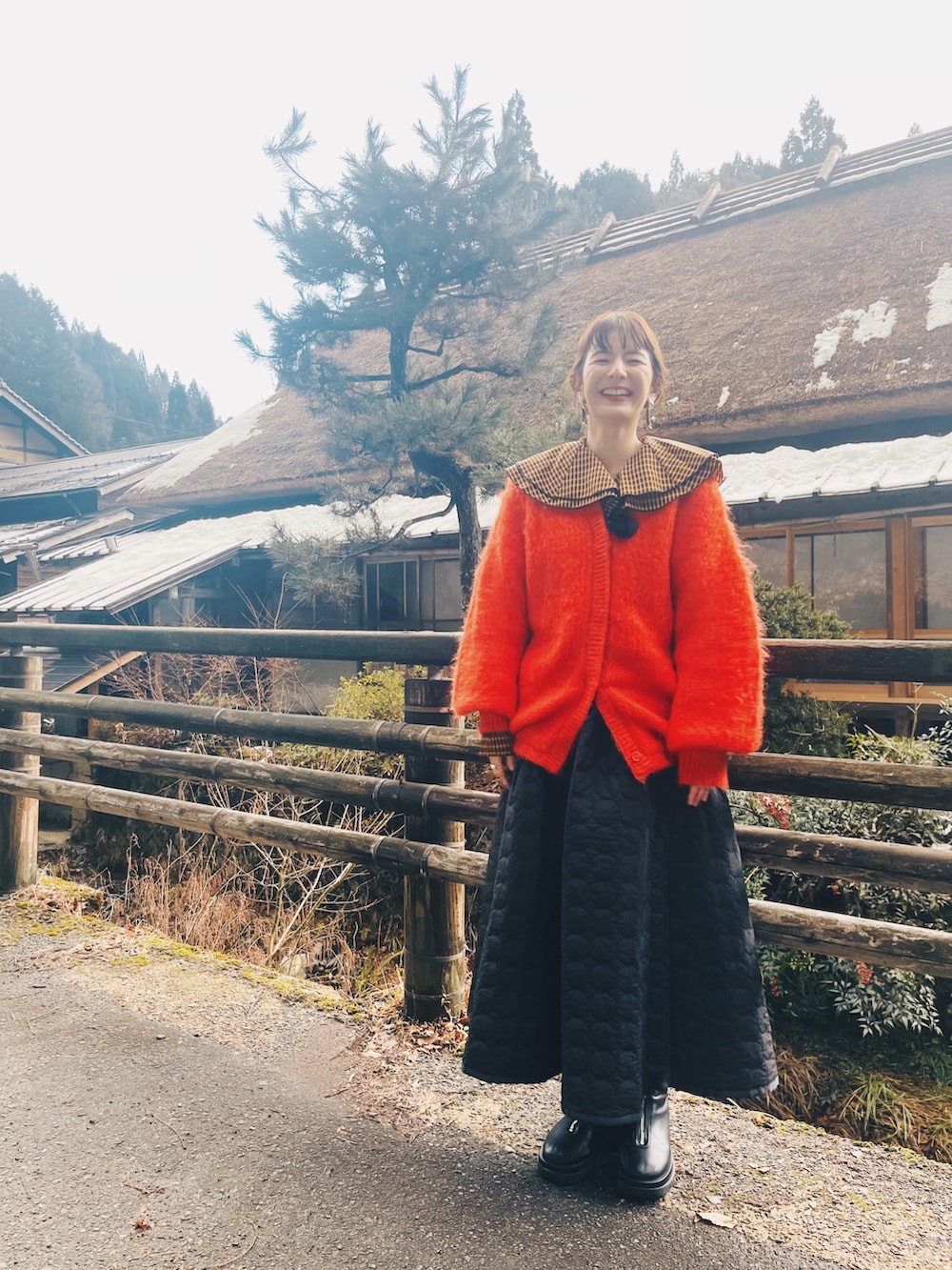 ブラック系のスカート、ブラック系のシューズ、オレンジ系のカーディガン/ボレロを着用したレディースの冬コーディネートの3枚目の写真