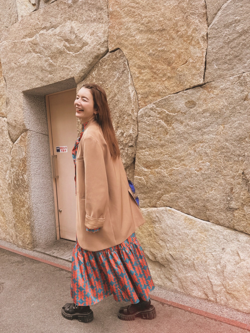 ブルー系のワンピース、ブラック系のサンダル、ベージュ系のノーカラージャケットを着用したレディースの春コーディネートの2枚目の写真