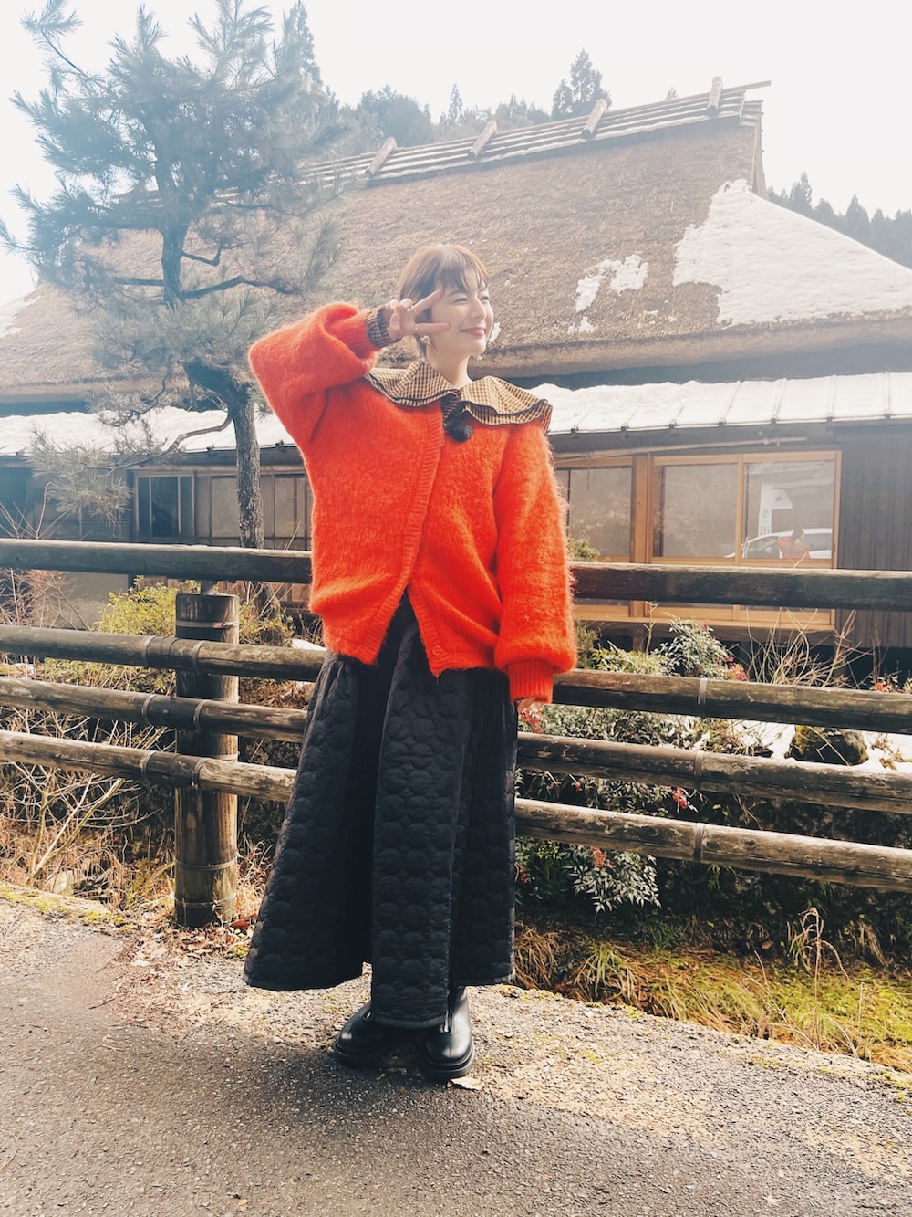 ブラック系のスカート、ブラック系のシューズ、オレンジ系のカーディガン/ボレロを着用したレディースの冬コーディネートの2枚目の写真