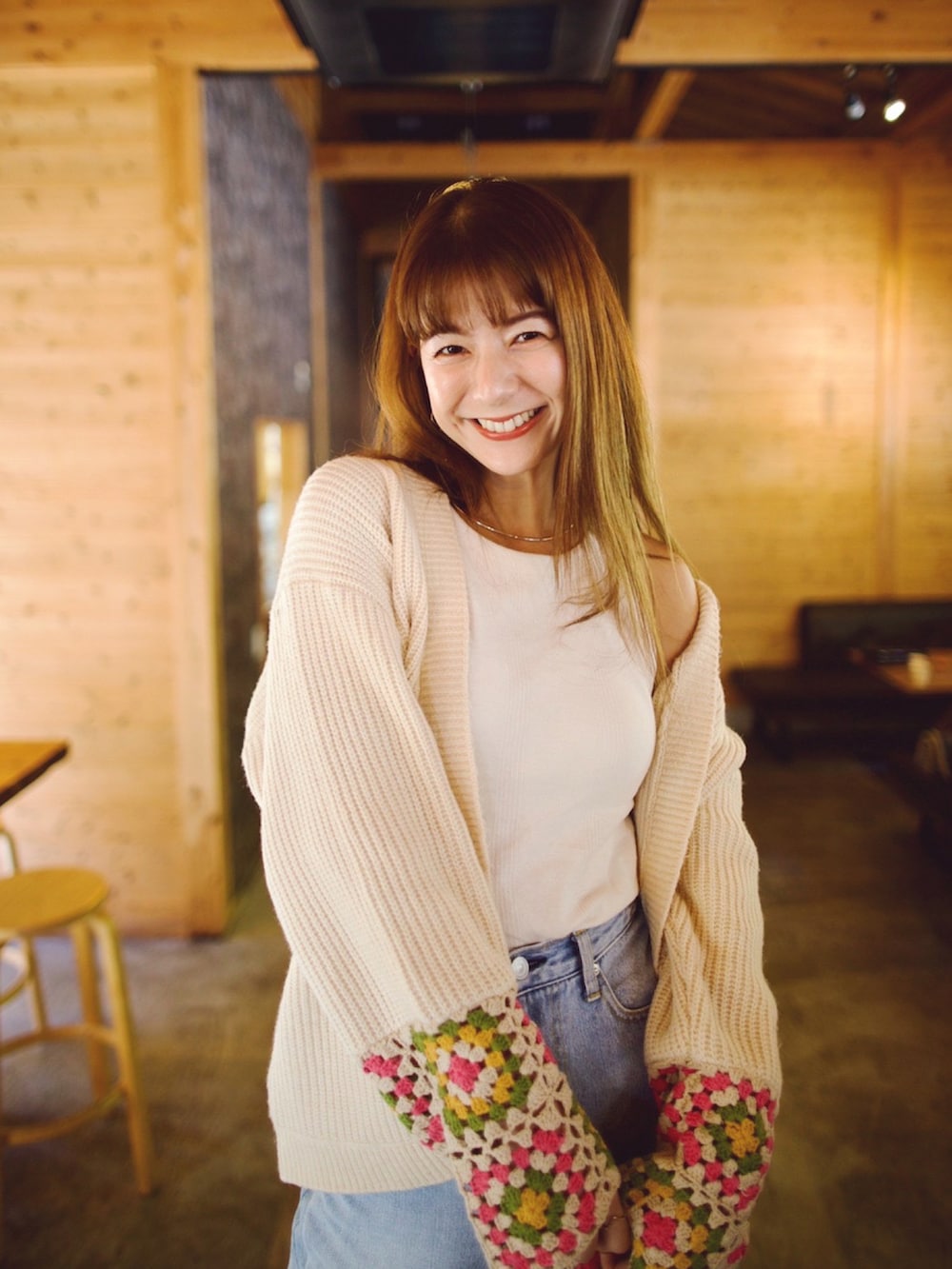 ベージュ系のカーディガン/ボレロ、ベージュ系のパンプス、ブルー系のデニムパンツを着用したレディースの秋コーディネートの2枚目の写真