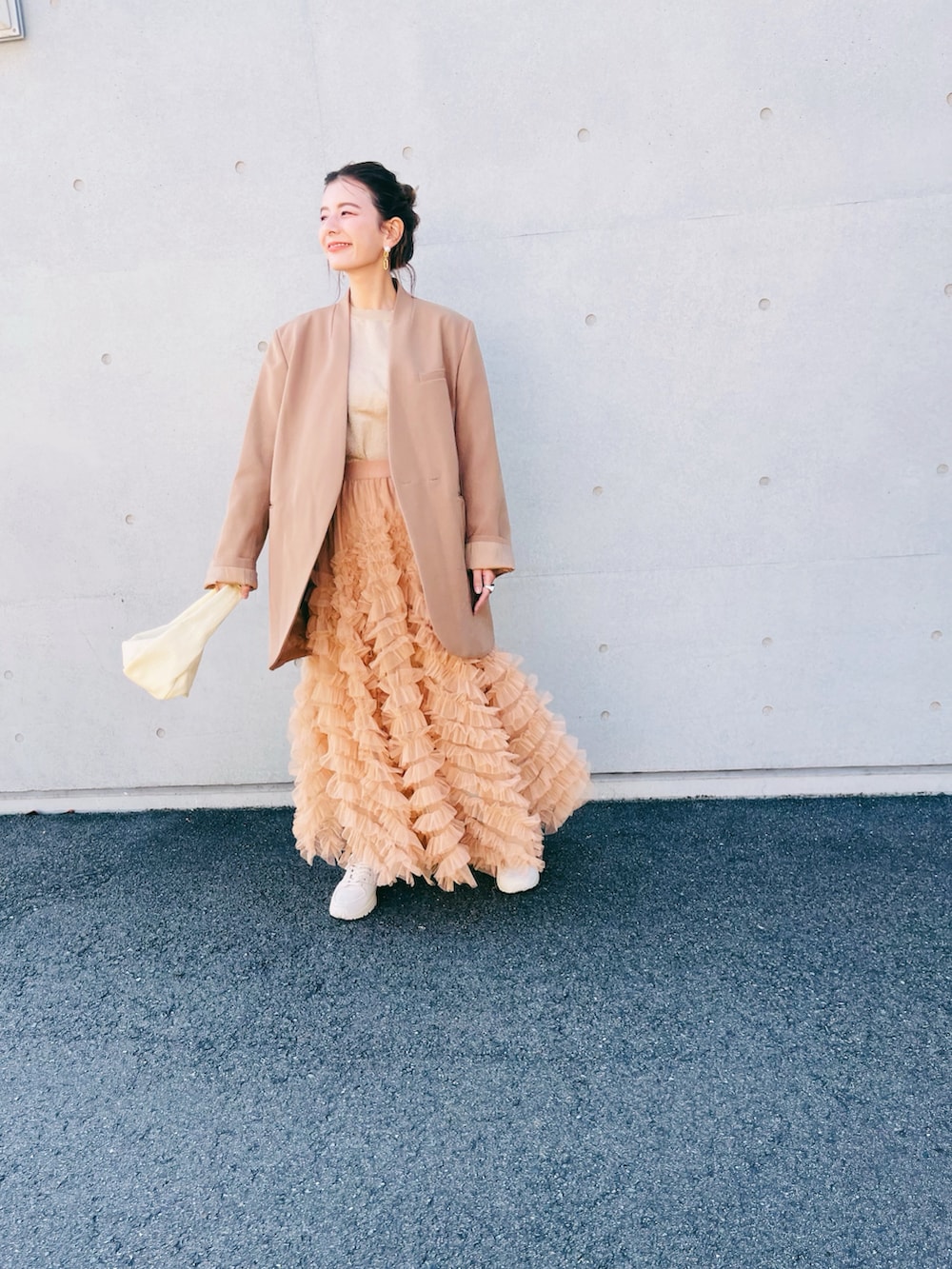 ブラック系のスカート、ベージュ系のハンドバッグ、ベージュ系のノーカラージャケットを着用したレディースの秋コーディネートの3枚目の写真