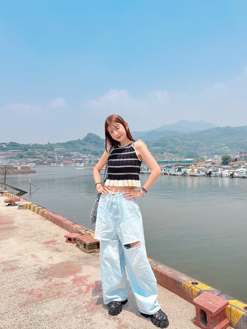 ブラック系のTシャツ/カットソー、ブルー系のデニムパンツ、ブラック系のサンダルを着用したレディースの夏コーディネートの2枚目の写真