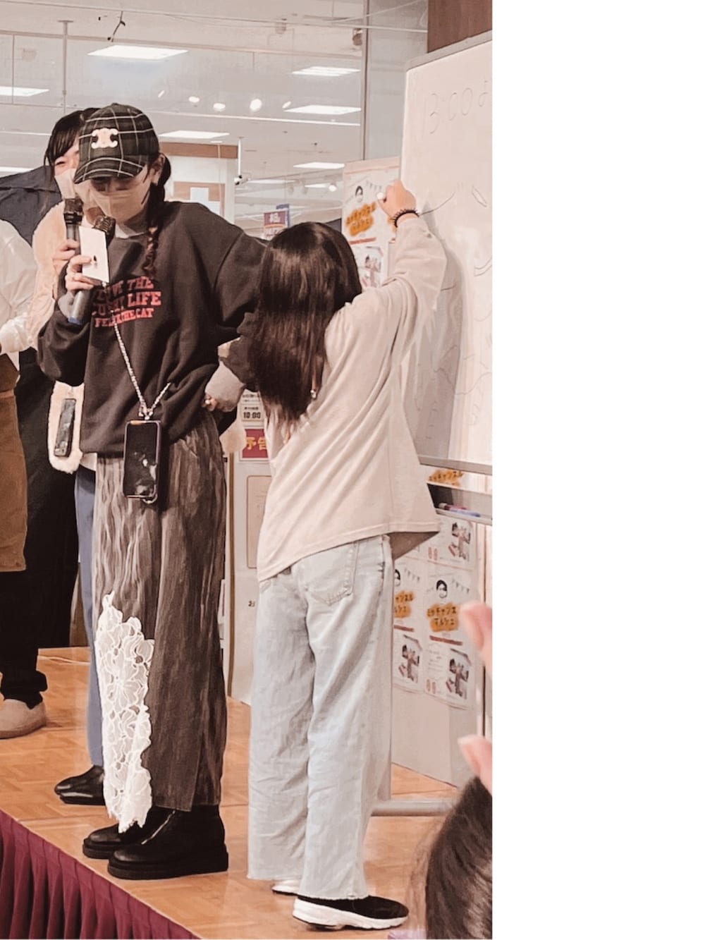 グレー系のスカート、パープル系のスマホケース/カバー、グリーン系のキャップを着用したレディースの冬コーディネートの2枚目の写真