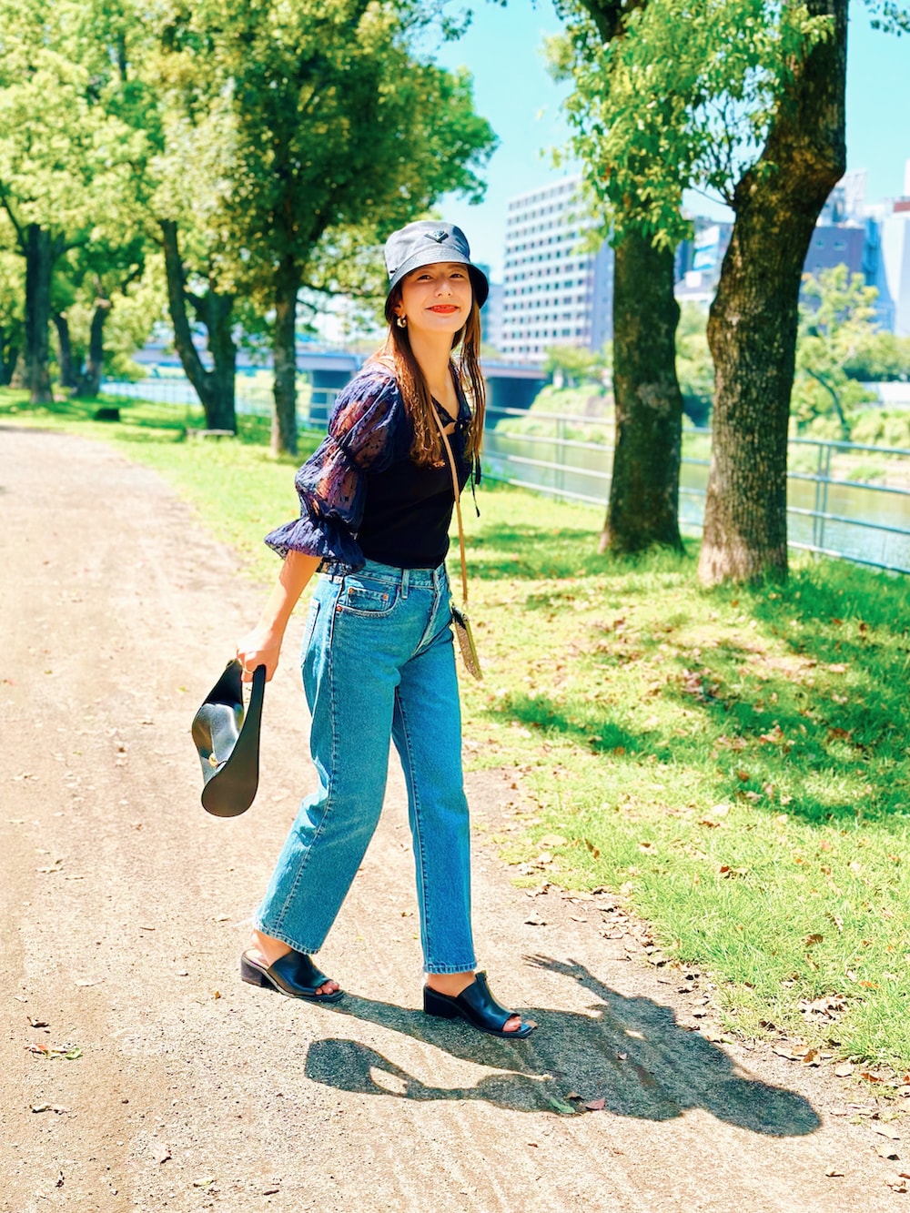 ブルー系のデニムパンツ、ブラック系のタンクトップ、ブラック系のサンダルを着用したレディースの秋コーディネートの3枚目の写真