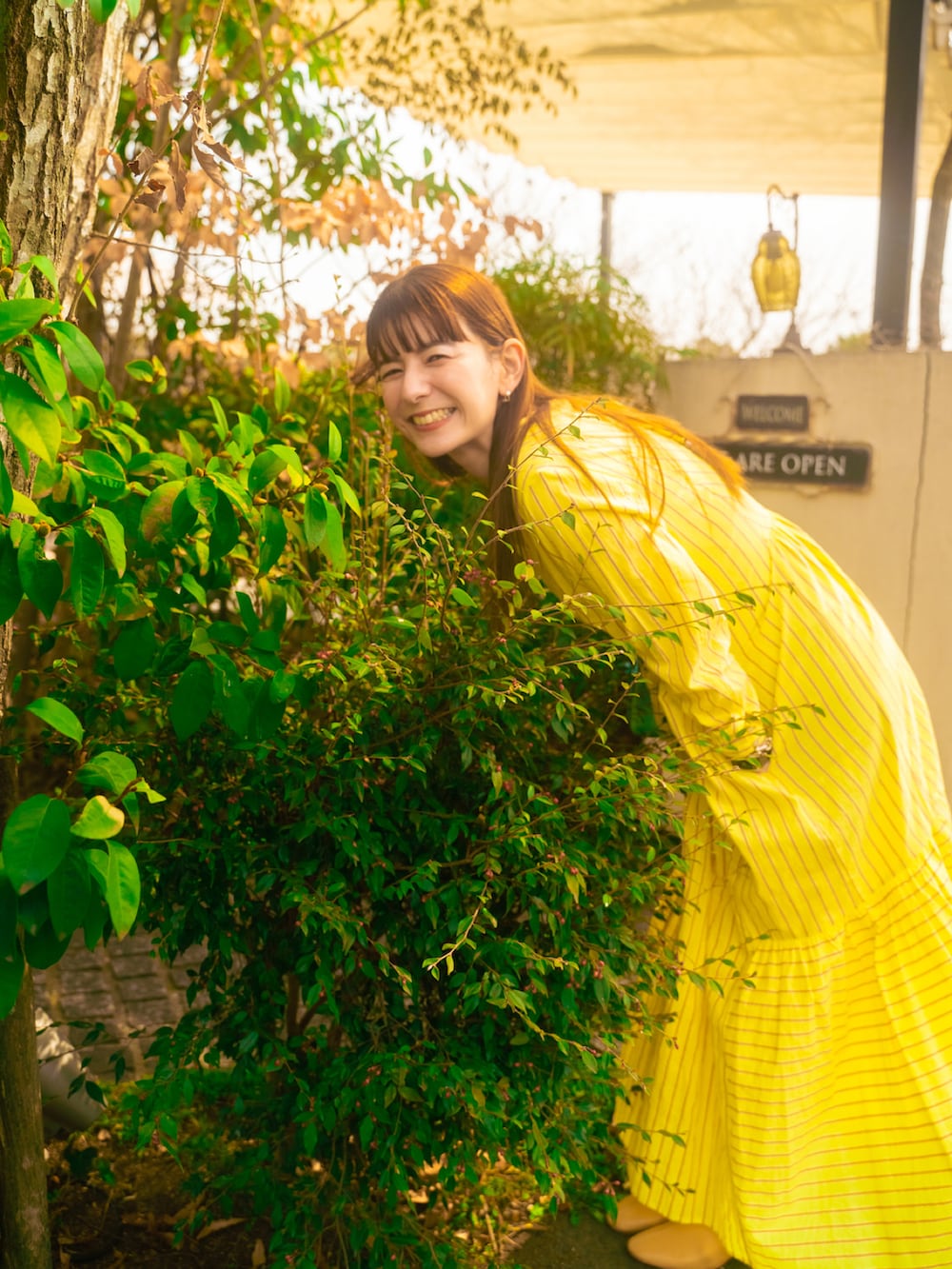 グリーン系のワンピース、ベージュ系のブーツ、ブルー系のバッグを着用したレディースの春コーディネートの3枚目の写真