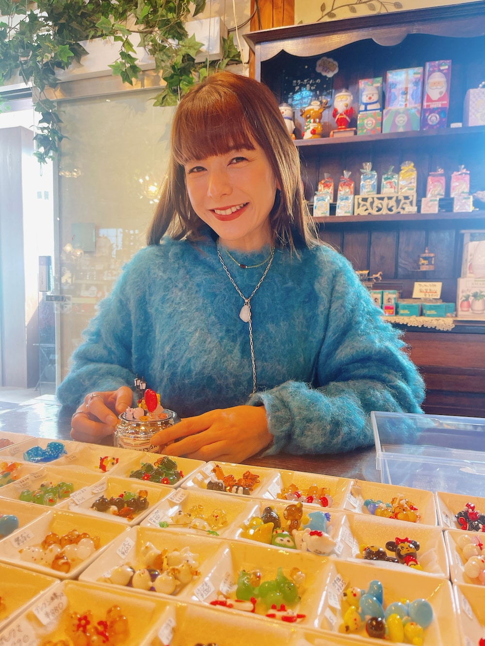 ブルー系のニット/セーター、ブラック系のスカート、ゴールド系のチョーカーを着用したレディースの冬コーディネートの2枚目の写真