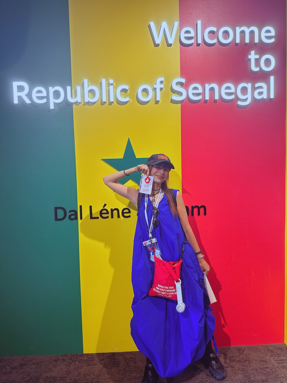 ブルー系のワンピース、レッド系のショルダーバッグ、ブラック系のスニーカーを着用したレディースの秋コーディネートの5枚目の写真