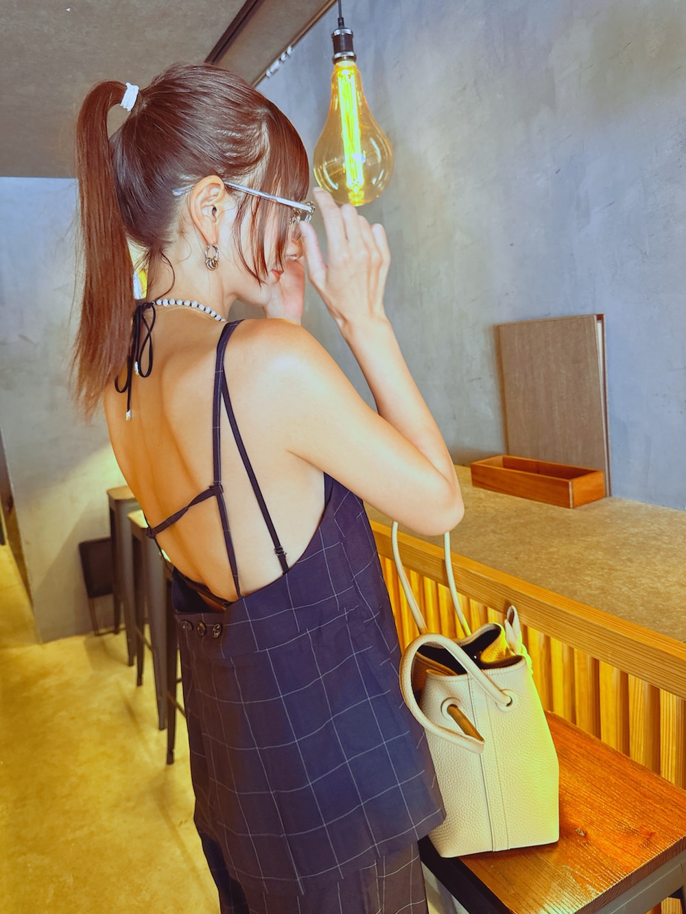 ベージュ系のバッグ、ブラック系のキャミソール、ブラック系のスラックスを着用したレディースの秋コーディネートの2枚目の写真