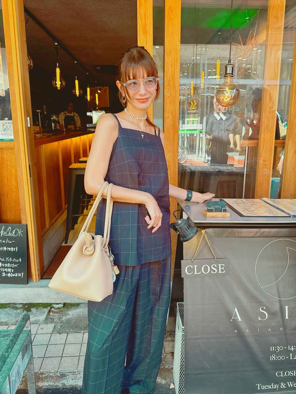 ベージュ系のバッグ、ブラック系のキャミソール、ブラック系のスラックスを着用したレディースの秋コーディネートの4枚目の写真