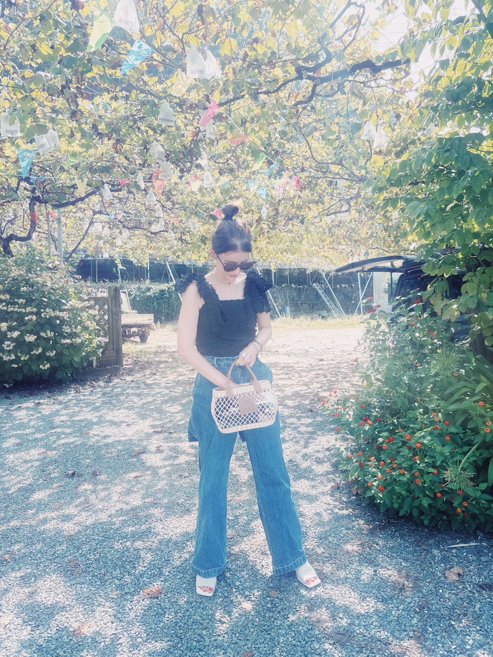 ブラック系のトップス、ホワイト系のサンダル、ベージュ系のバッグを着用したレディースの夏コーディネートの2枚目の写真