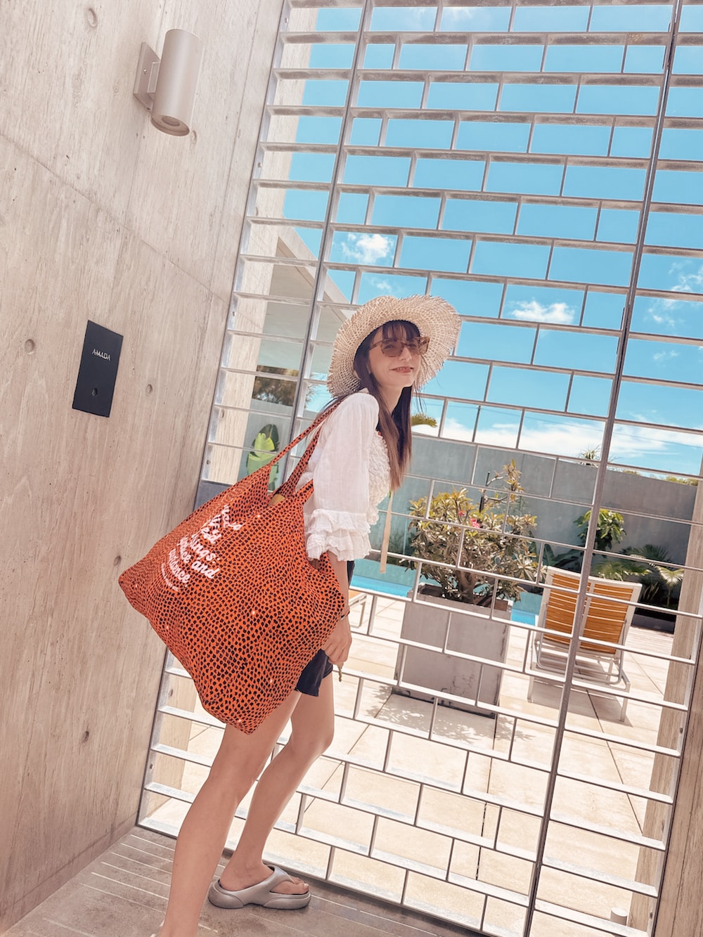 シルバー系のサンダル、ブルー系のトートバッグ、ブラック系の水着を着用したレディースの夏コーディネートの2枚目の写真