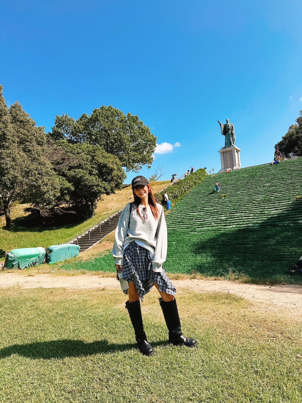 ブルー系のスカート、ブラック系のブーツ、グレー系のスウェットを着用したレディースの秋コーディネートの2枚目の写真