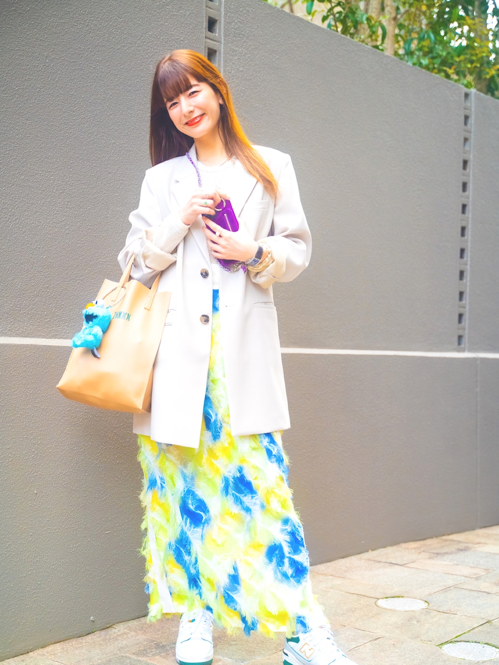 ベージュ系のテーラードジャケット、ホワイト系のTシャツ/カットソー、イエロー系のスカートを着用したレディースの春コーディネートの2枚目の写真