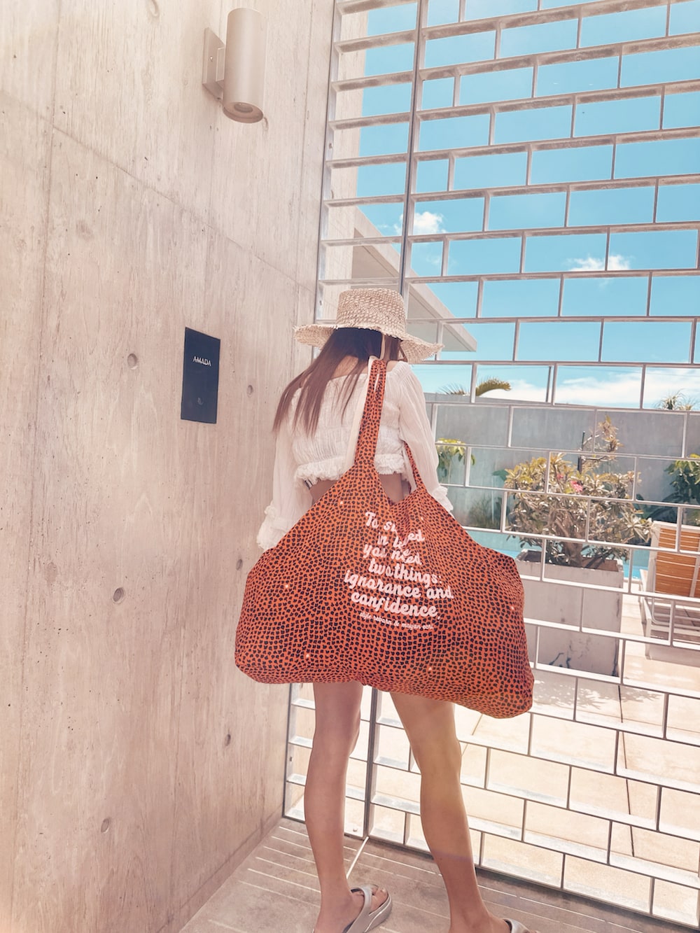 シルバー系のサンダル、ブルー系のトートバッグ、ブラック系の水着を着用したレディースの夏コーディネートの3枚目の写真