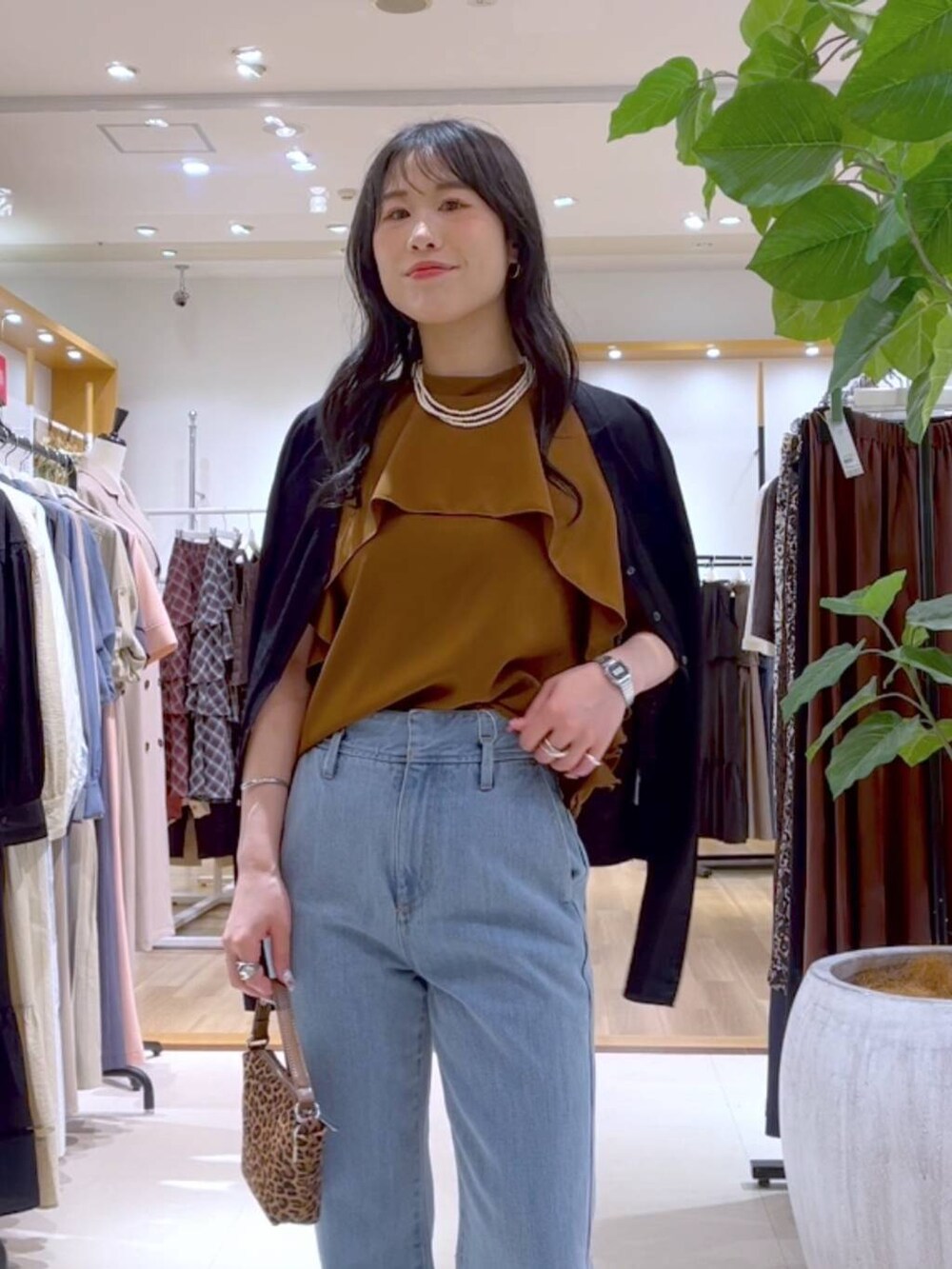 イエロー系のシャツ/ブラウス、ブラウン系のショルダーバッグ、ブルー系のデニムパンツを着用したレディースの夏コーディネートの2枚目の写真