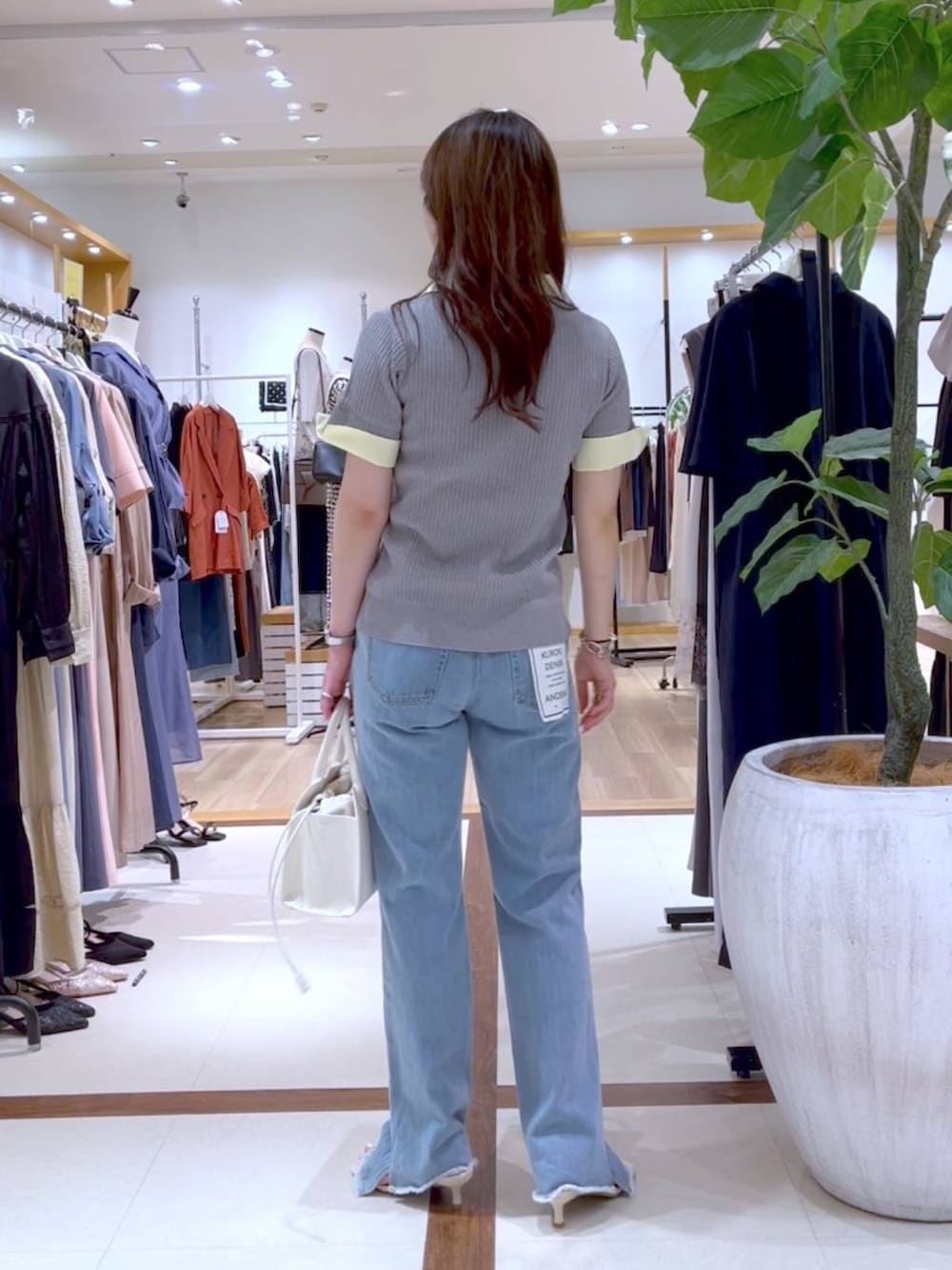 ブルー系のデニムパンツ、ホワイト系のトートバッグ、ベージュ系のサンダルを着用したレディースの夏コーディネートの3枚目の写真