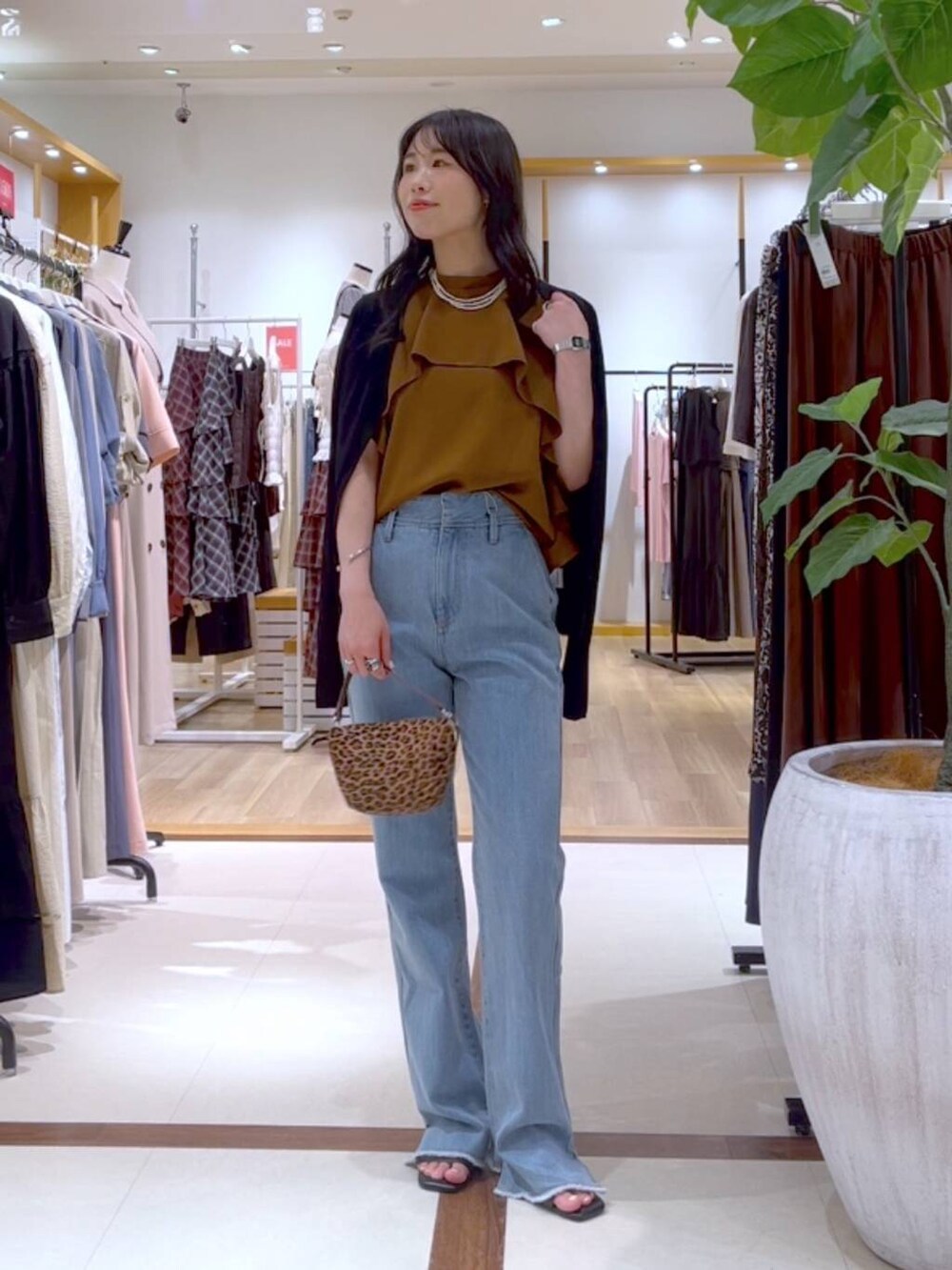 イエロー系のシャツ/ブラウス、ブラウン系のショルダーバッグ、ブルー系のデニムパンツを着用したレディースの夏コーディネートの4枚目の写真