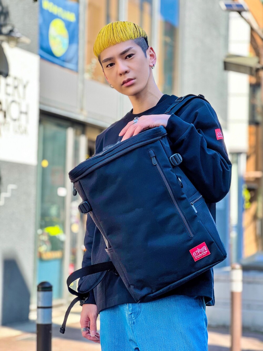 ブラック系のバックパック/リュック、ピンク系のスニーカー、ブルー系のデニムパンツを着用したメンズの春コーディネートの2枚目の写真