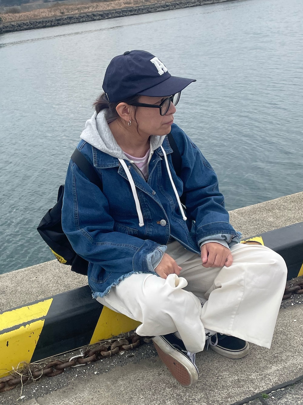 ブルー系のデニムジャケット、ブラック系のスニーカー、ホワイト系のチノパンツを着用したレディースの春コーディネートの3枚目の写真