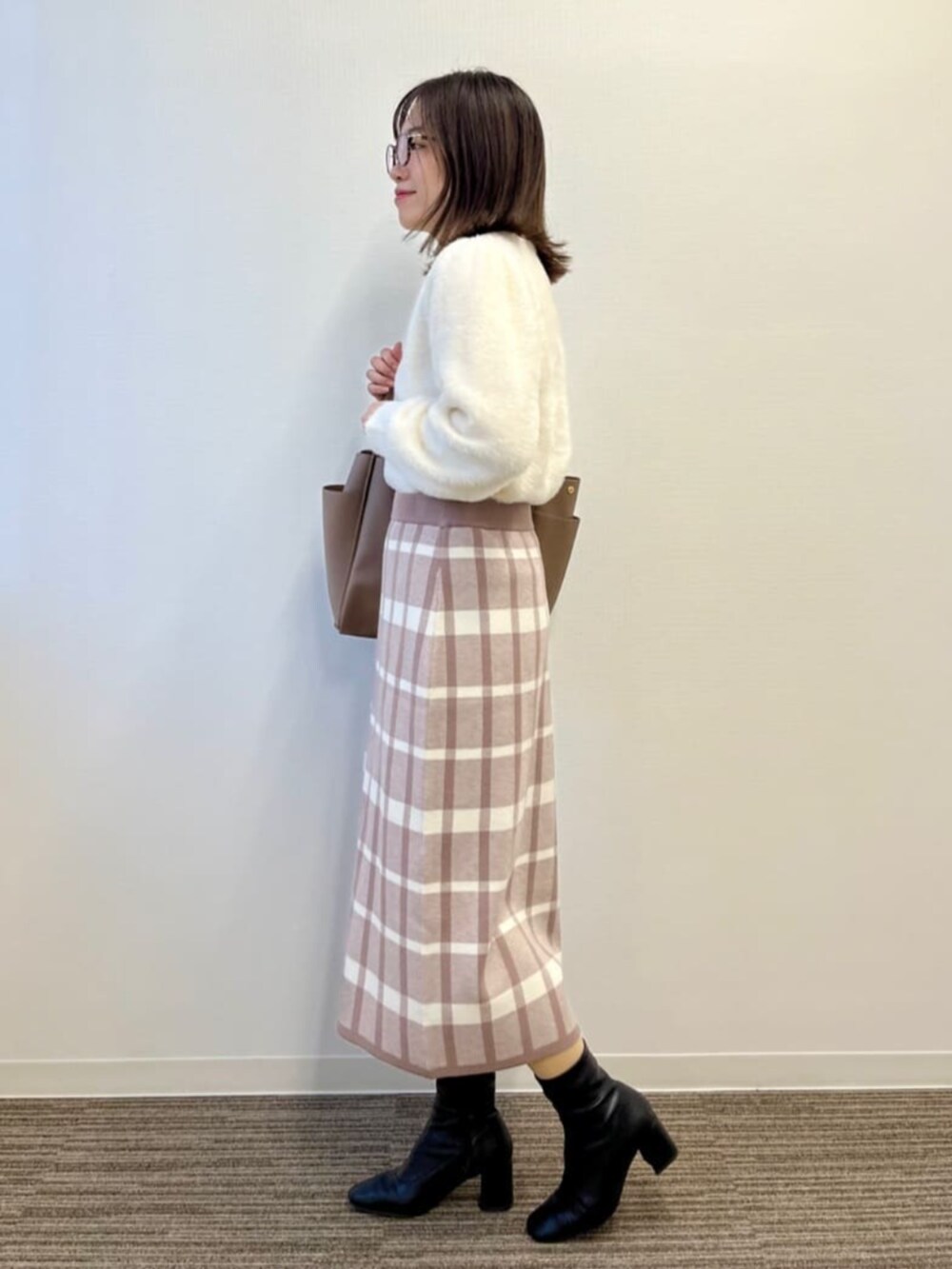 ベージュ系のセットアップ、ホワイト系のニット/セーター、ブラウン系のトートバッグを着用したレディースの冬コーディネートの2枚目の写真